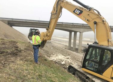 man standing next to excavator on IH 35E site